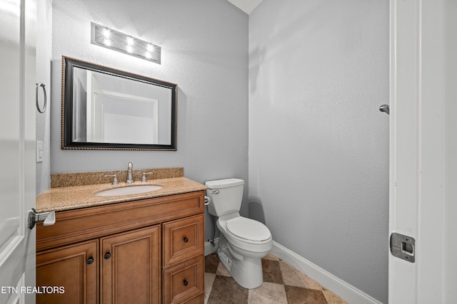half bath featuring toilet, baseboards, and vanity