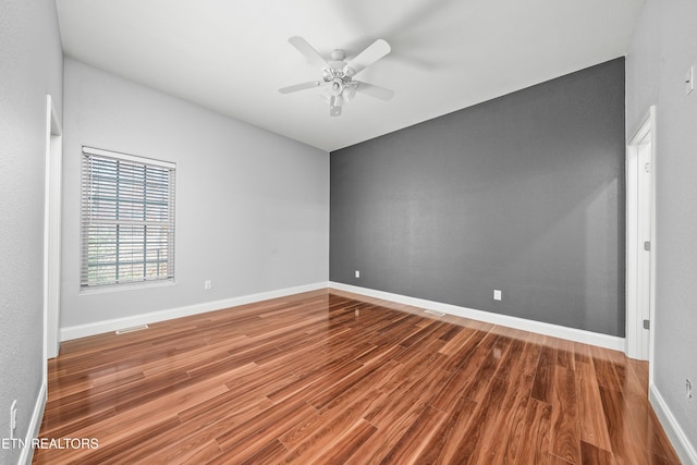 unfurnished room featuring ceiling fan, baseboards, visible vents, and wood finished floors