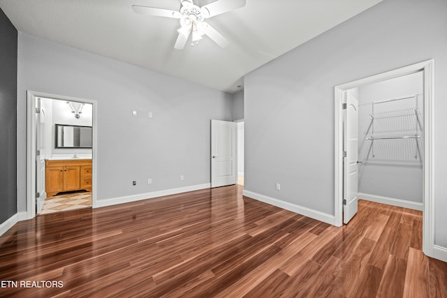 unfurnished bedroom featuring a spacious closet, dark hardwood / wood-style floors, ceiling fan, and connected bathroom