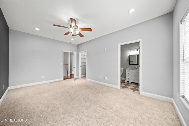 unfurnished bedroom featuring light colored carpet, ceiling fan, and connected bathroom