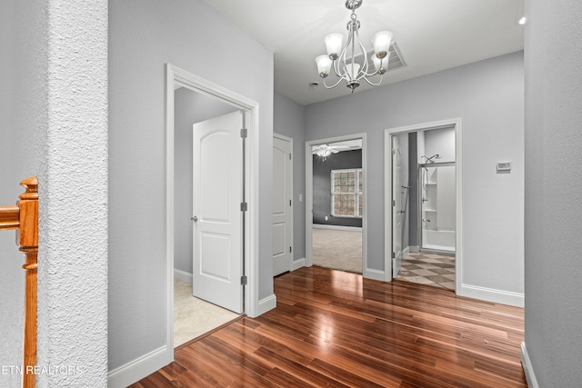 corridor featuring a chandelier, baseboards, and wood finished floors