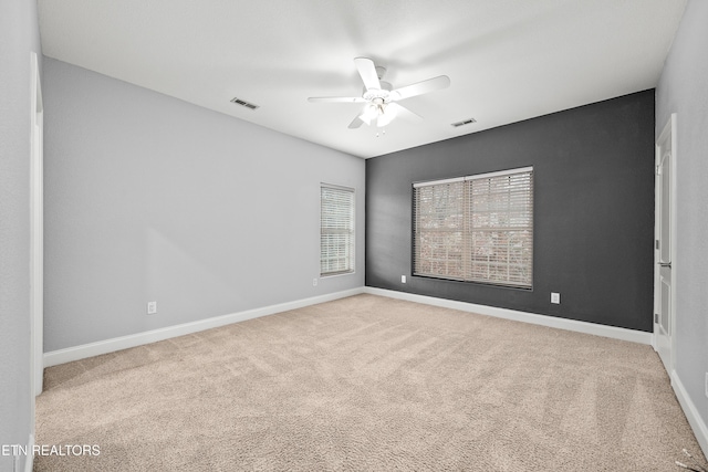 carpeted empty room featuring visible vents, baseboards, and a ceiling fan