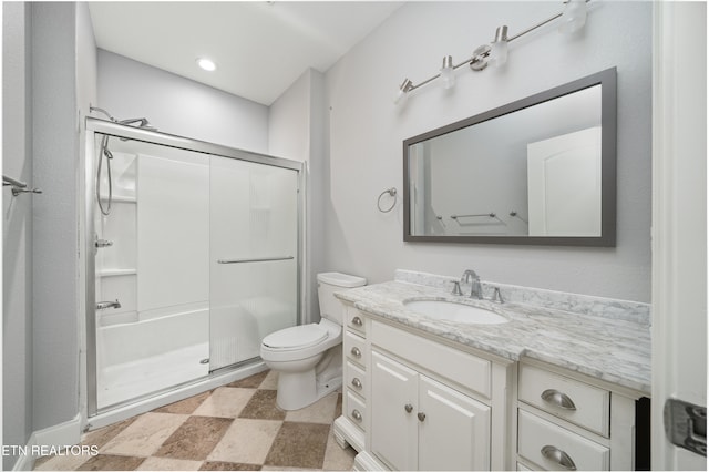 bathroom featuring a shower with door, vanity, and toilet