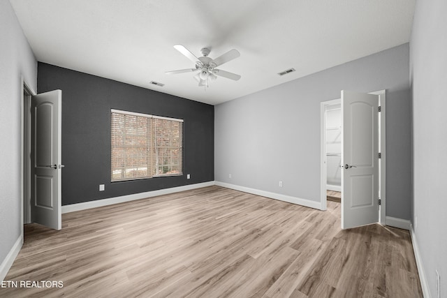 unfurnished bedroom featuring a ceiling fan, visible vents, light wood-style flooring, and baseboards