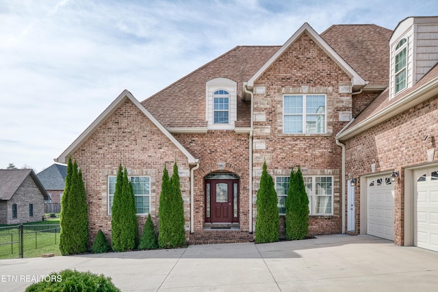 view of front of home featuring fence, brick siding, driveway, a garage, and a shingled roof