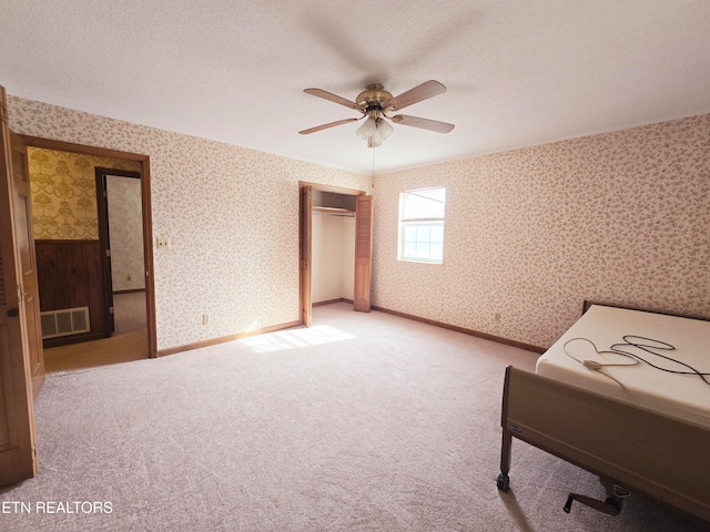 unfurnished room featuring ceiling fan, a textured ceiling, and light carpet