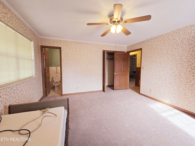 unfurnished bedroom with ornamental molding, light carpet, ceiling fan, and ensuite bath