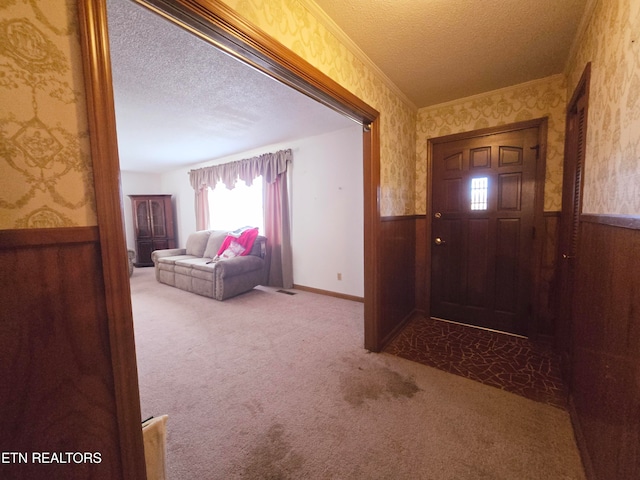 entryway with wood walls, a textured ceiling, and light colored carpet