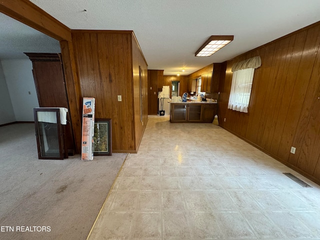 interior space with wooden walls, a textured ceiling, and light colored carpet