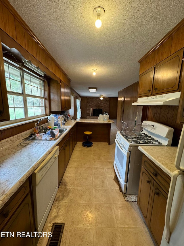 kitchen featuring wood walls, white appliances, and a textured ceiling