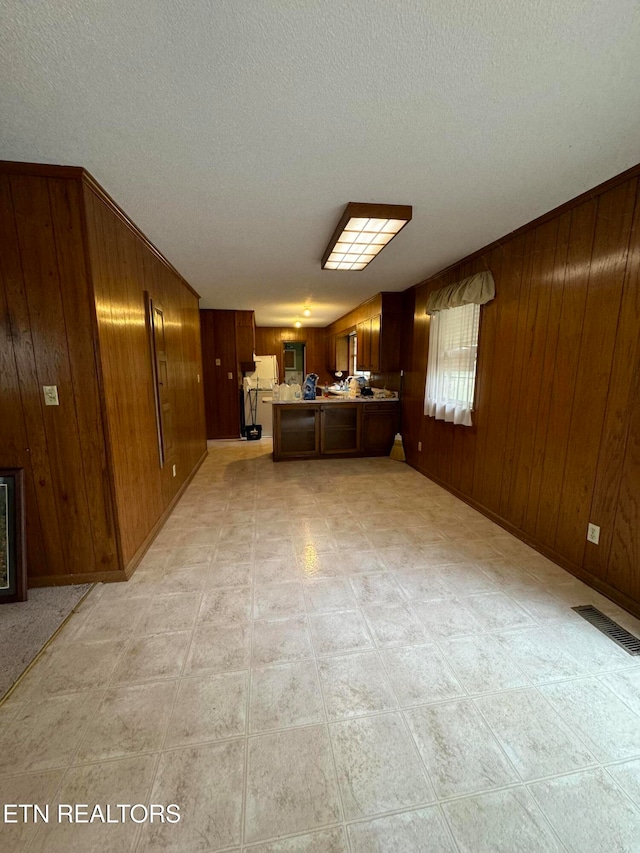 unfurnished living room featuring wood walls and a textured ceiling