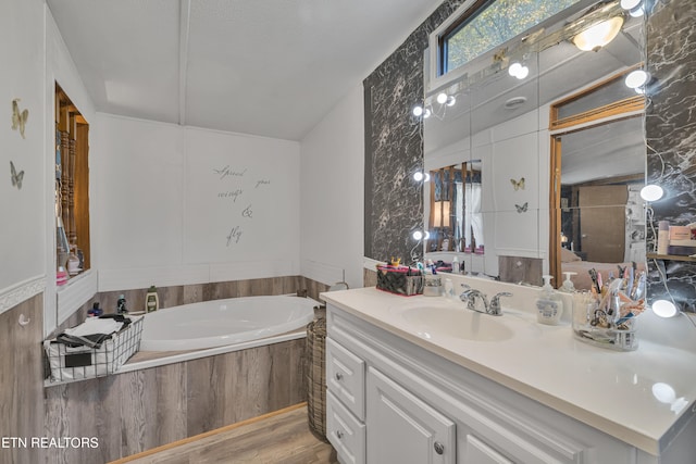 bathroom featuring vanity, wood-type flooring, and a relaxing tiled tub