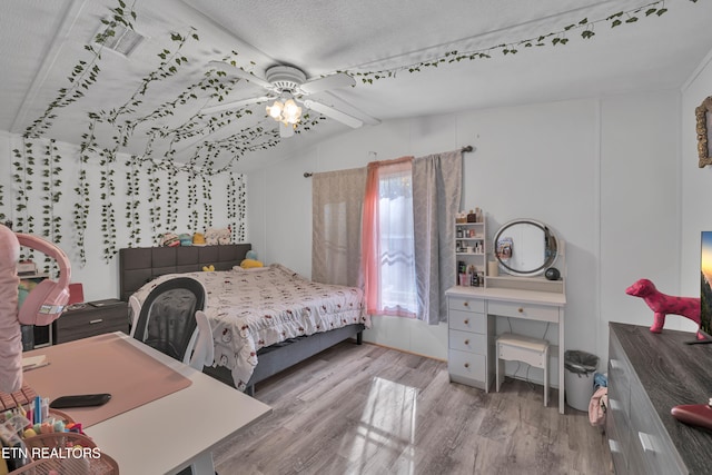 bedroom with ceiling fan, a textured ceiling, light hardwood / wood-style flooring, and vaulted ceiling