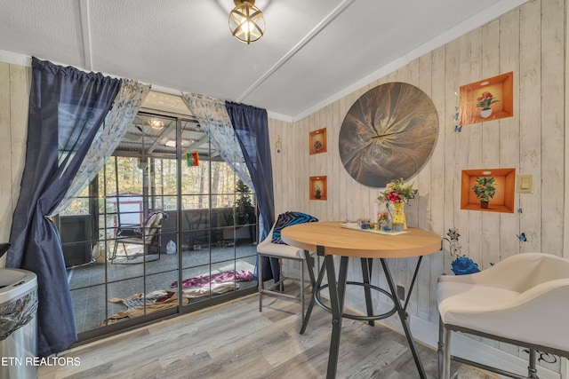 dining space featuring wood-type flooring and wooden walls