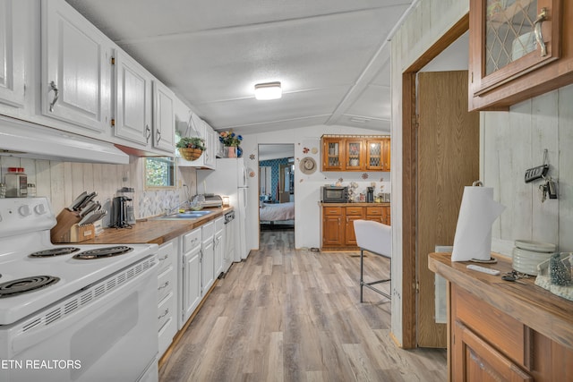 kitchen featuring vaulted ceiling, wooden walls, electric range, white cabinetry, and light wood-type flooring