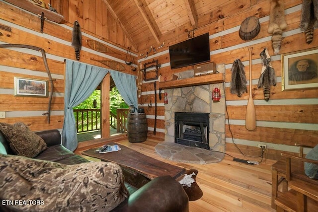 living room with lofted ceiling with beams, a stone fireplace, wood walls, wood ceiling, and hardwood / wood-style floors