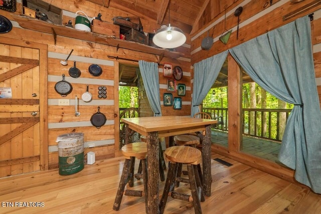 dining space featuring wood ceiling, wooden walls, hardwood / wood-style flooring, and vaulted ceiling with beams