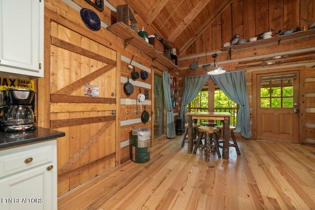 dining space featuring wood walls, light wood-type flooring, lofted ceiling, and wood ceiling