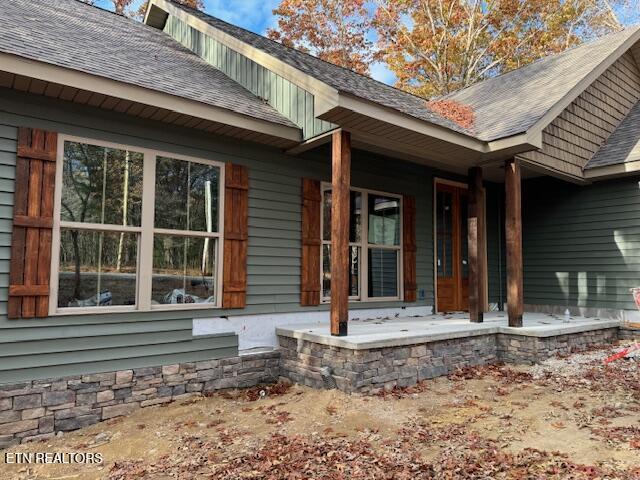 property entrance featuring a shingled roof