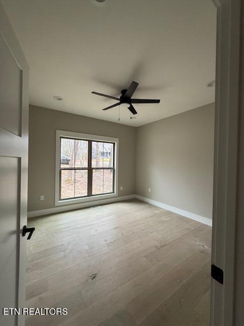 empty room with hardwood / wood-style flooring, ceiling fan, and baseboards