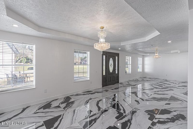 entryway featuring a tray ceiling, a wealth of natural light, a textured ceiling, and a notable chandelier