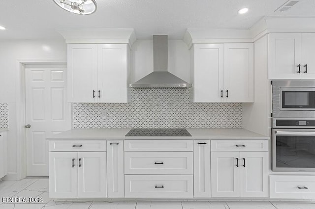 kitchen with white cabinets, appliances with stainless steel finishes, backsplash, and wall chimney exhaust hood