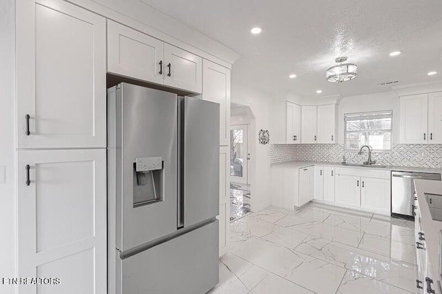 kitchen with white cabinets, decorative backsplash, sink, and stainless steel appliances