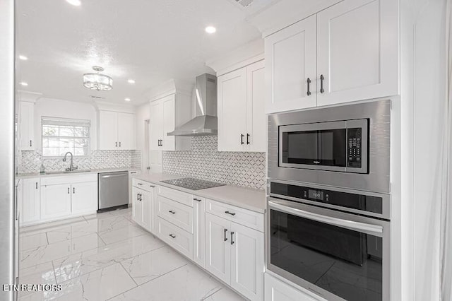 kitchen featuring decorative backsplash, appliances with stainless steel finishes, sink, wall chimney range hood, and white cabinets