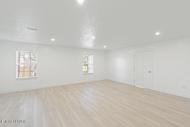 spare room featuring light hardwood / wood-style floors and a textured ceiling