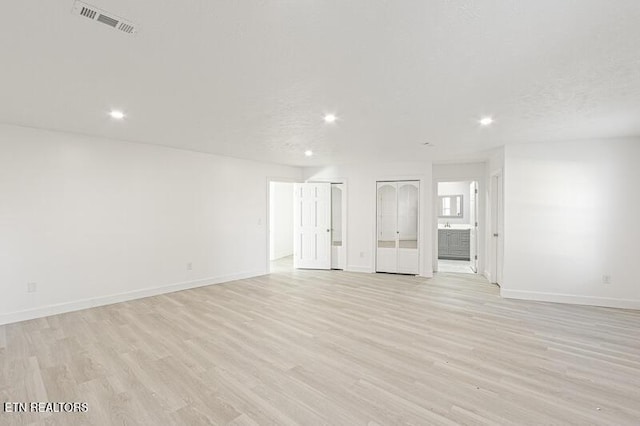 unfurnished living room with light hardwood / wood-style flooring and a textured ceiling