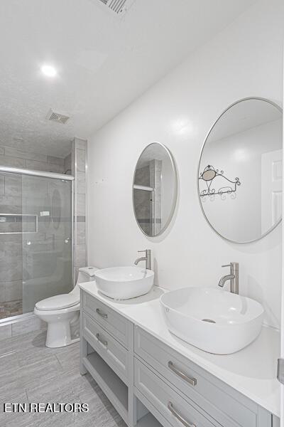 bathroom with vanity, toilet, and a shower with shower door