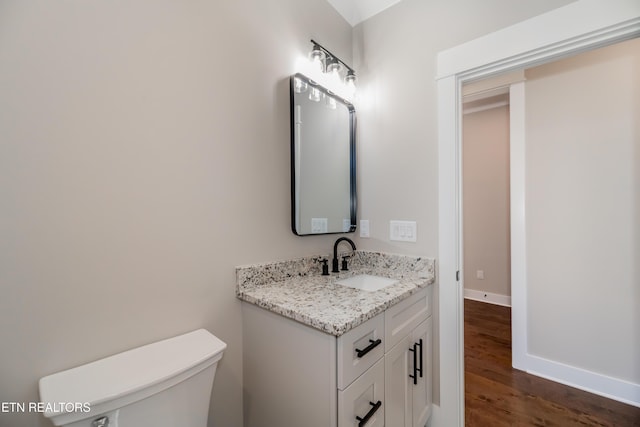 bathroom with vanity, toilet, and hardwood / wood-style floors