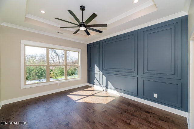 unfurnished bedroom featuring a tray ceiling, ornamental molding, and dark hardwood / wood-style flooring