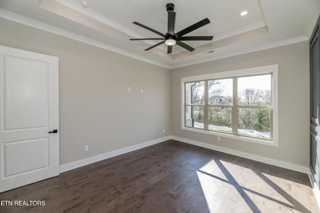 empty room featuring dark hardwood / wood-style flooring, ceiling fan, crown molding, and a raised ceiling