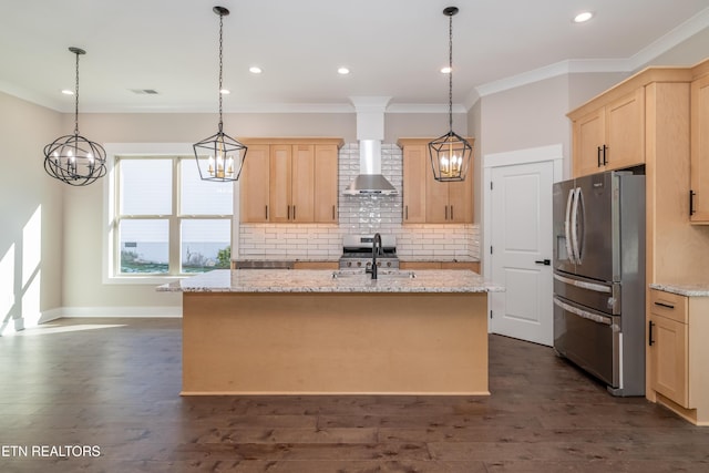 kitchen with wall chimney range hood, appliances with stainless steel finishes, a kitchen island with sink, and light brown cabinets