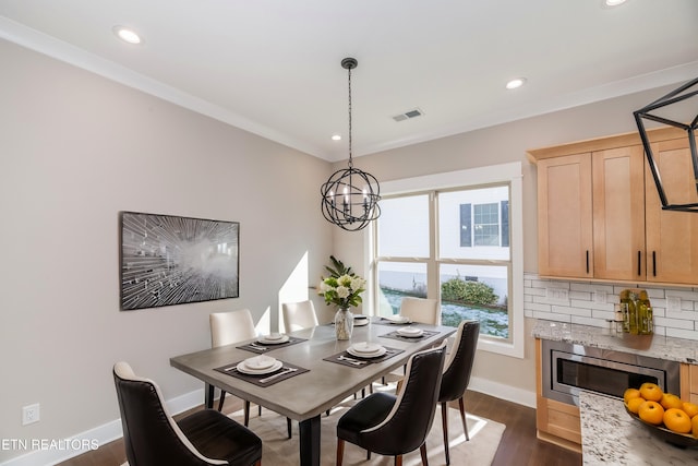 dining area featuring ornamental molding, dark wood-type flooring, and a notable chandelier