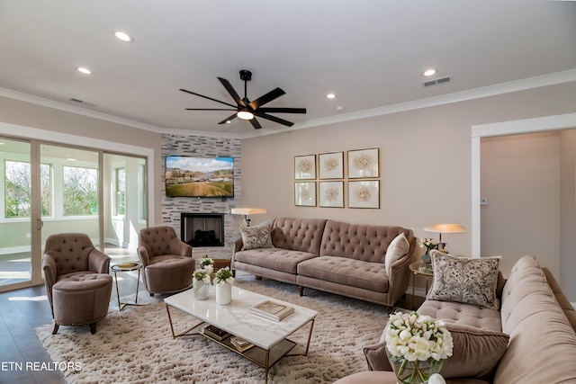 living room with ceiling fan, hardwood / wood-style flooring, crown molding, and a large fireplace