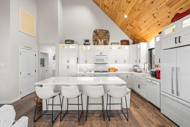 kitchen featuring white appliances, white cabinetry, a kitchen island, and high vaulted ceiling