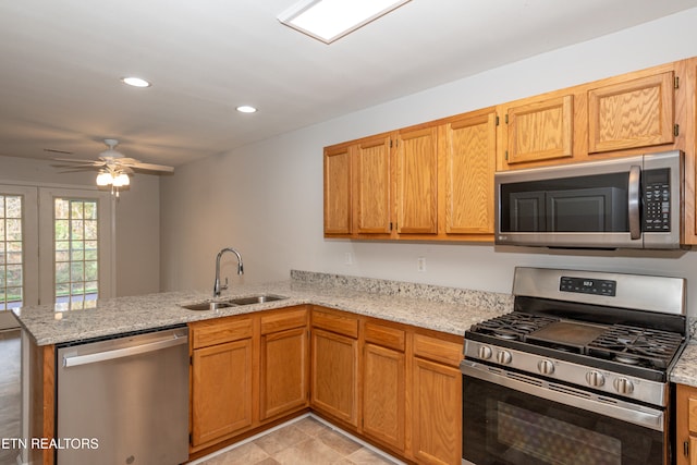 kitchen with stainless steel appliances, kitchen peninsula, sink, ceiling fan, and light stone countertops