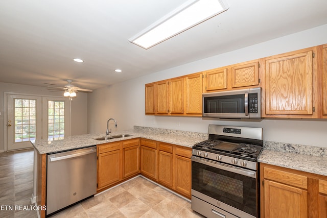 kitchen featuring stainless steel appliances, sink, light stone counters, kitchen peninsula, and ceiling fan