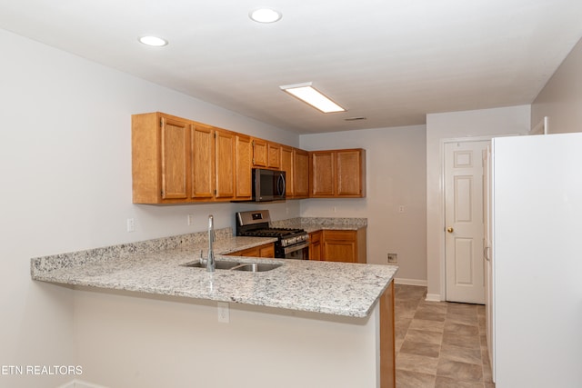 kitchen with kitchen peninsula, appliances with stainless steel finishes, sink, and light stone counters