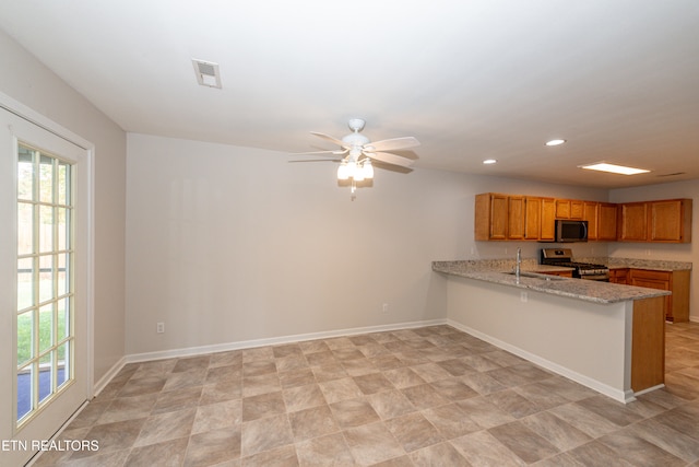 kitchen with stainless steel appliances, light stone counters, kitchen peninsula, sink, and ceiling fan