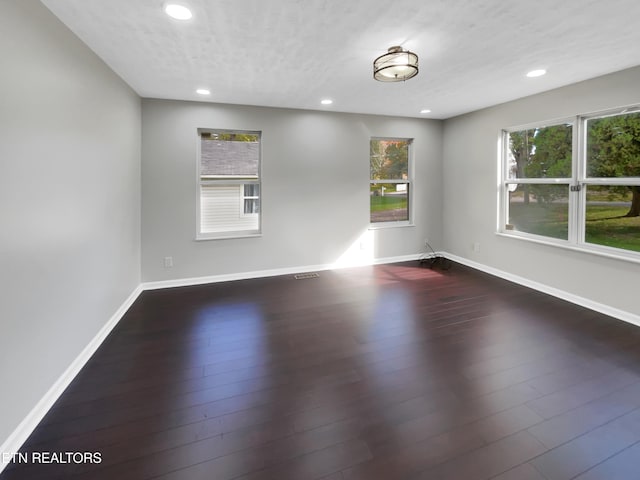 empty room featuring a textured ceiling and dark hardwood / wood-style floors