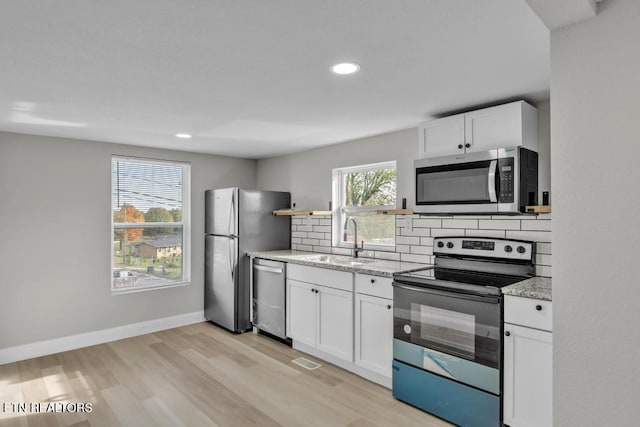 208 Collins St, Loudon, TN 37774 - kitchen with light hardwood / wood-style floors, decorative backsplash, sink, white cabinetry, and appliances with stainless steel finishes