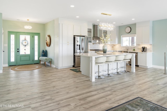 kitchen with white cabinets, hanging light fixtures, appliances with stainless steel finishes, a kitchen island, and a chandelier