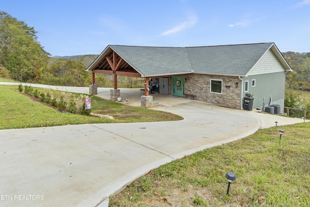 view of front of property with cooling unit, a front lawn, and a carport