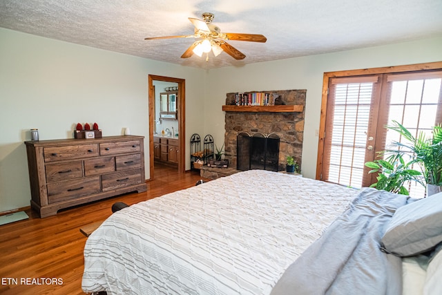 bedroom featuring a textured ceiling, ensuite bath, hardwood / wood-style flooring, and ceiling fan