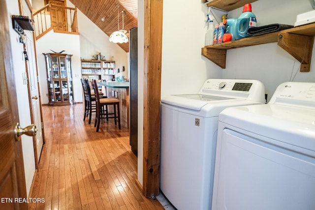 clothes washing area featuring washing machine and clothes dryer and light hardwood / wood-style floors