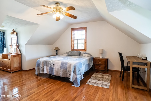 bedroom featuring wood-type flooring, vaulted ceiling, ceiling fan, and a textured ceiling