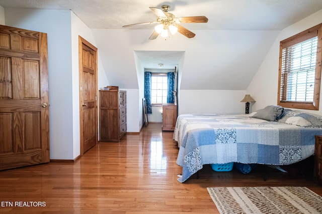 bedroom featuring ceiling fan, wood-type flooring, multiple windows, and lofted ceiling